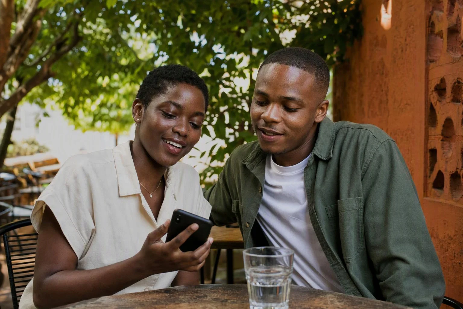 Two friends sharing a moment over a phone at an outdoor café